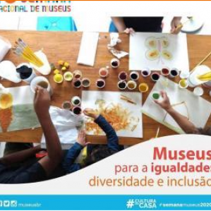 Foto com várias crianças mexendo com tintas em cima de uma mesa de cor amadeirada