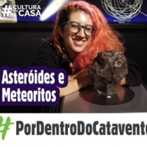 Foto de uma mulher com cabelo rosa e óculos sorrido ao lado de um asteroide 