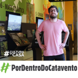 Homem de camiseta rosa sorrind. Ao fundo sala do Biomas do Brasil localizado no Museu Catavento