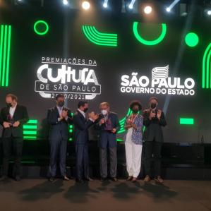 Homens de terno, ao fundo a imagem do logotipo do governo do Estado de São Paulo