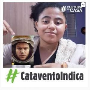 Mulher negra com cabelos presos, apontando para imagem da capa do filme