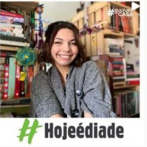 Mulher sorrindo, ao fundo uma estante cheia de livros